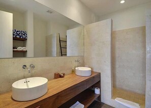 A modern bathroom with two sinks, a large mirror, and a shower area.