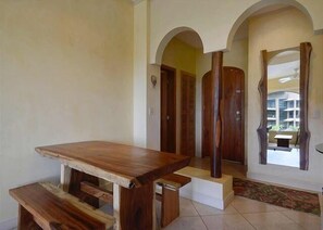 Un comedor con una mesa de madera y bancos, un arco de entrada y vistas al exterior.