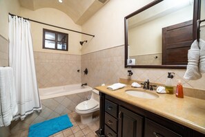A bathroom with a bathtub, toilet, sink, and a large mirror.