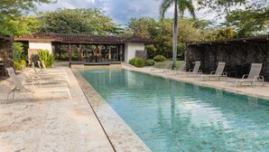 A swimming pool with lounge chairs and a covered seating area. - Villa Lucia (Tamarindo)