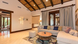 A spacious living room with a large sofa, a round coffee table, and a patterned rug. - Villa Lucia (Tamarindo)
