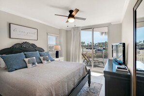 A bedroom with a bed, a ceiling fan, a TV, and a balcony with a view. - Waterscape A135, Ground Floor, Family Fun!, Great Resort! (Fort Walton Beach)