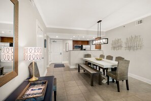 A modern dining area with a white table and wicker chairs, a bench, and a decorative lamp. - Waterscape A135, Ground Floor, Family Fun!, Great Resort! (Fort Walton Beach)