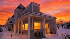 A two-story house with a covered porch and a snow-covered yard. - Islands View Condo- Waterfront (Saint Ignace)
