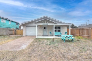 A single-story house with a covered porch, a garage, and a small patio area with a picnic table and chairs.
