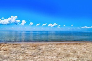 Een strand met helder water en een zandstrand onder een blauwe lucht.