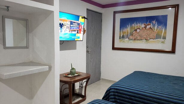A hotel room with two beds, a television, a framed painting, and a small table with a plant. - Zac NicteMx House / ESTUDIO SISAL (Cancun)