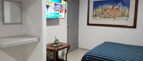 Ein Hotelzimmer mit zwei Betten, einem Fernseher, einem gerahmten Gemälde und einem kleinen Tisch mit einer Pflanze.