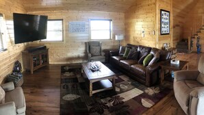 Un accogliente interno di una baita con zona soggiorno, sala da pranzo e cucina.
