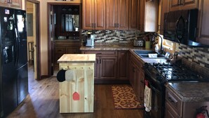 Una cucina con mobili in legno, un frigorifero nero, un forno a microonde, un fornello e una macchina da caffè.