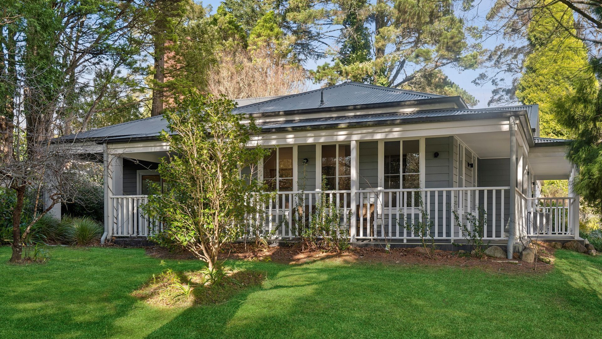 A two-story house with a porch, surrounded by trees and a well-maintained lawn.