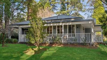 A two-story house with a porch, surrounded by trees and a well-maintained lawn.