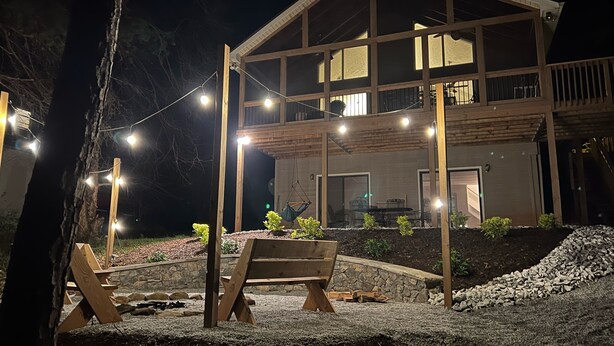 A two-story wooden house with a balcony, string lights, and outdoor seating. - LAKEFRONT HARTWELL! Good dogs welcome! Covered dock, fire pit, kayaks! (Westminster)