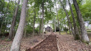 A forested area with a wooden pathway leading to a building. - LAKEFRONT HARTWELL! Good dogs welcome! Covered dock, fire pit, kayaks! (Westminster)