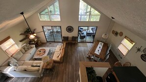 A spacious loft with high ceilings, a large sliding glass door leading to an outdoor patio, a cozy seating area with a sofa and coffee table, and a dining table with chairs. - LAKEFRONT HARTWELL! Good dogs welcome! Covered dock, fire pit, kayaks! (Westminster)