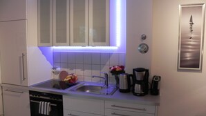 Una cocina moderna con armarios blancos, un lavamanos de acero inoxidable y un horno empotrado.