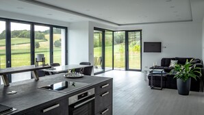 Eine moderne Küche mit einer großen Kochinsel, einem Essbereich und einem Wohnbereich mit Sofa und Fernseher.