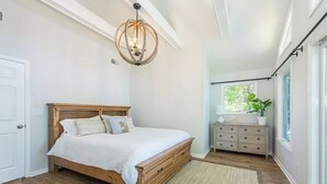 Un dormitorio con una cama de madera, una mesita de noche, un aparador y una ventana con una planta.