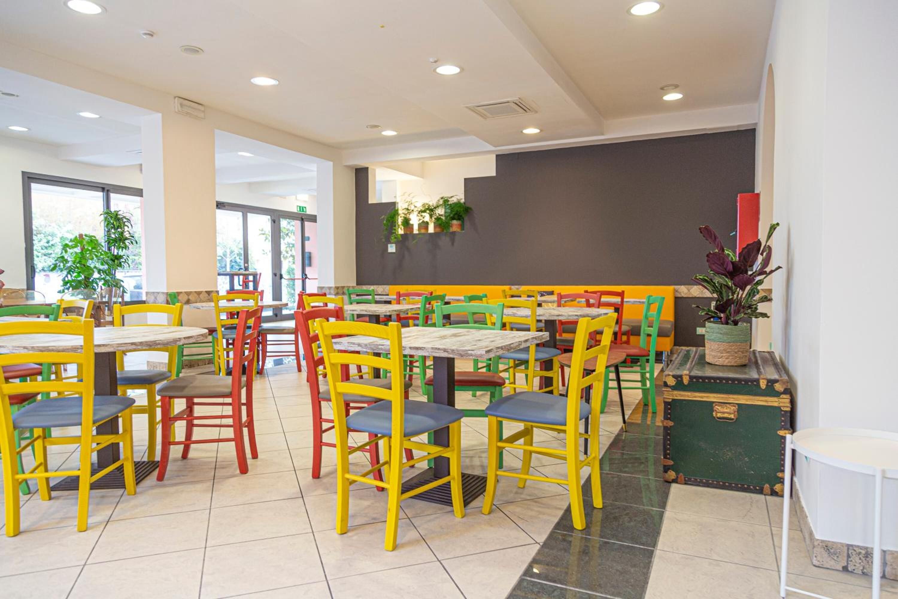 A brightly lit indoor dining area with multiple tables and chairs in various colors.
