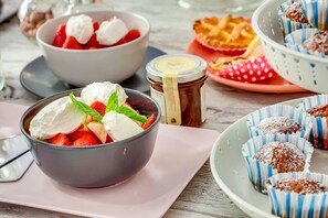 A dessert table with bowls of strawberries and whipped cream, a jar of jam, and chocolate-covered treats. - MareHome Brunch&Beauty - Adults Only (Cesenatico)