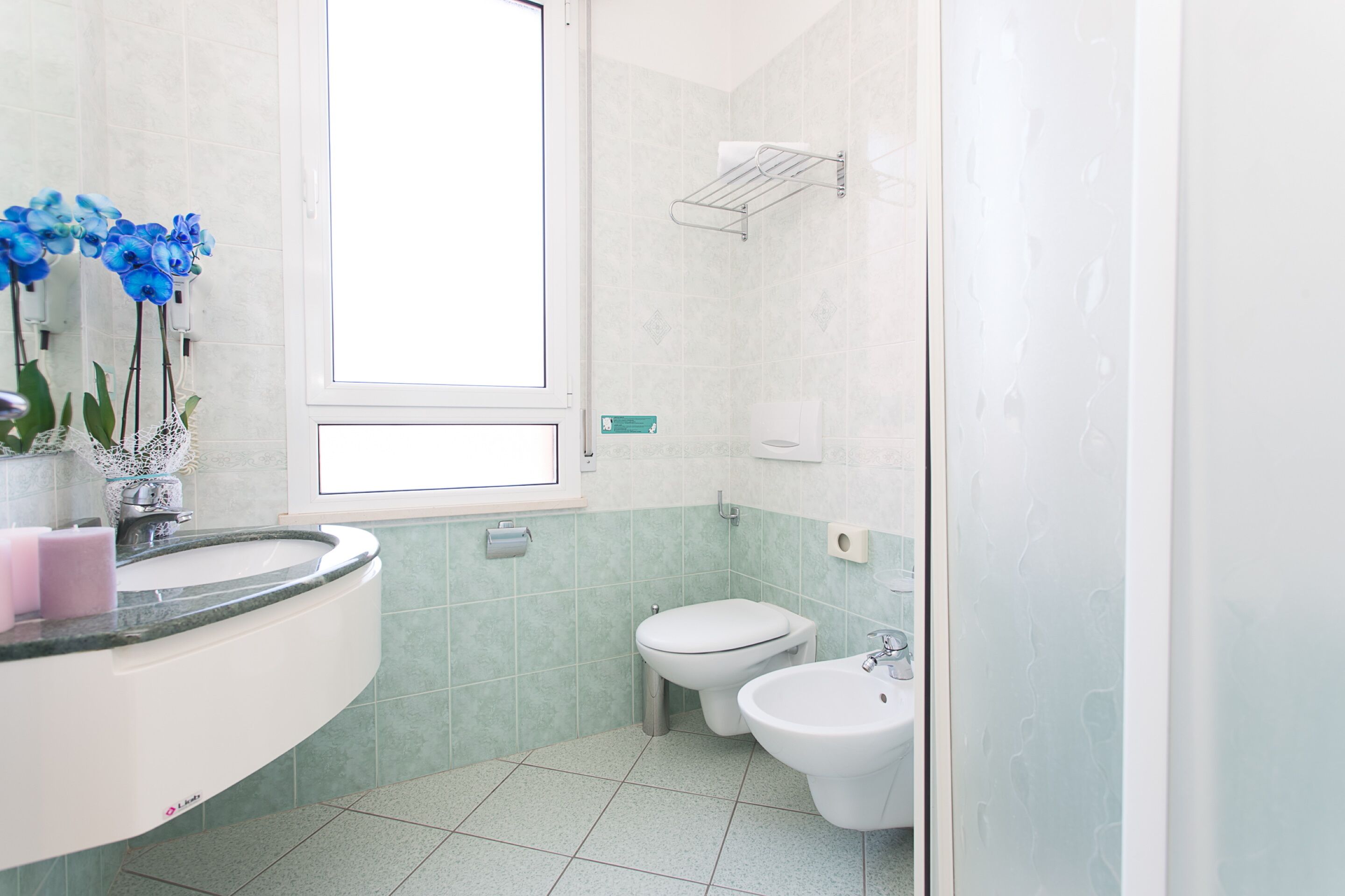 Een badkamer met een wastafel, toilet, bidet en een raam.