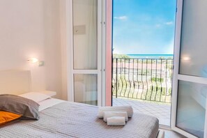 Une chambre à coucher avec un lit, une fenêtre et vue sur la plage.