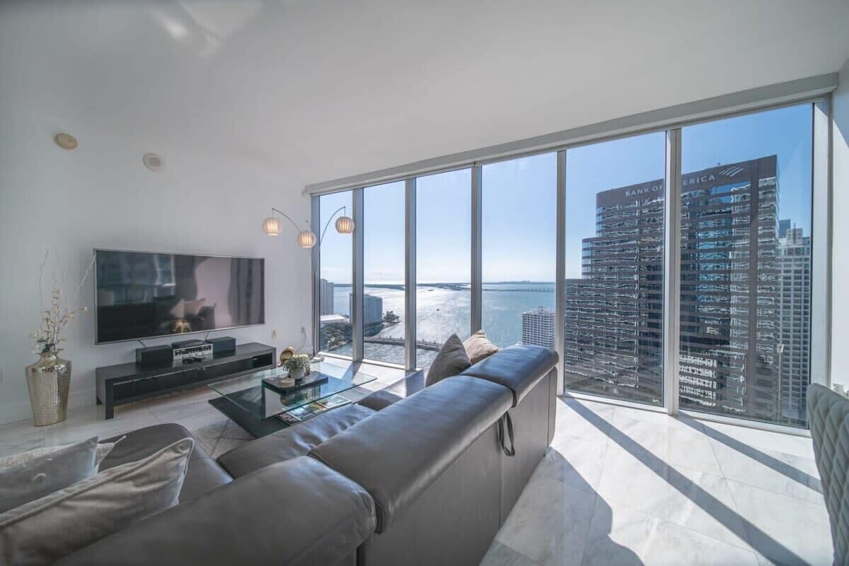 A modern living room with a large TV, a sofa, and a glass coffee table.