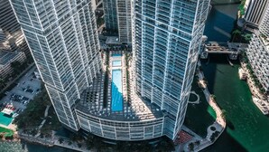 Un edificio alto con un cortile interno, una piscina e un porto turistico.