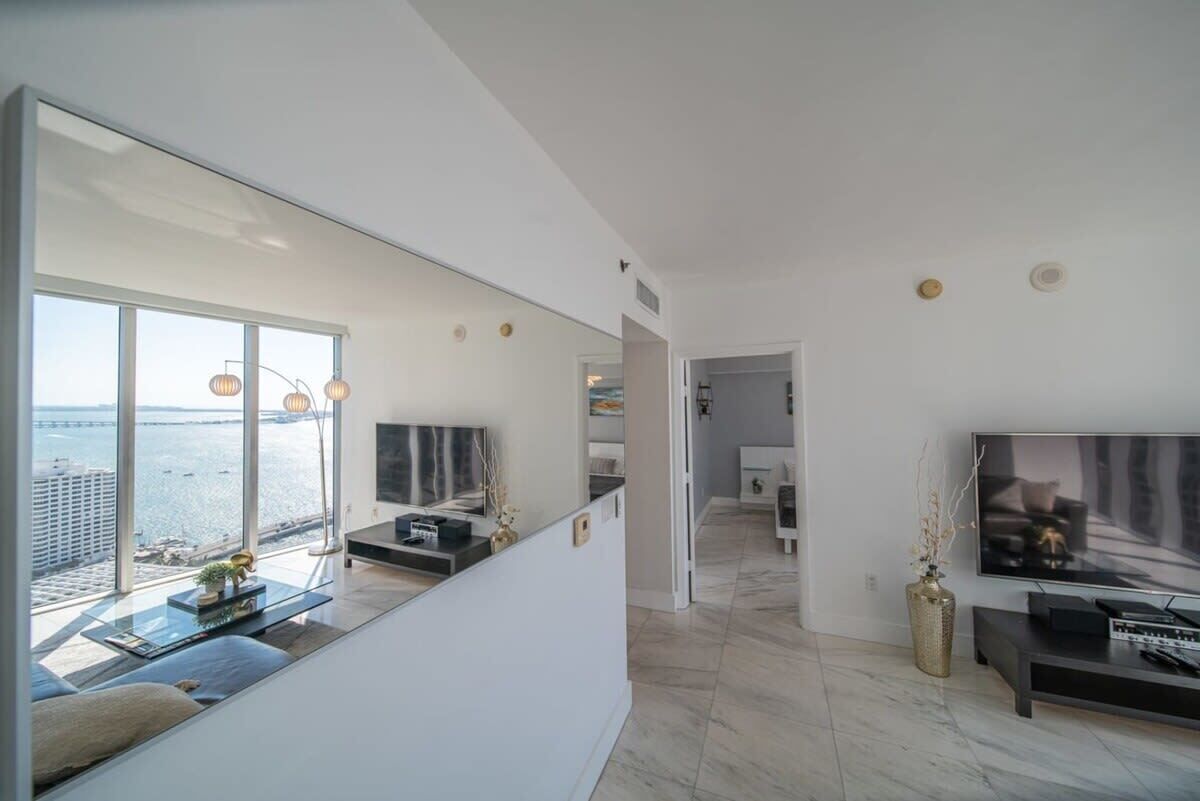 Een moderne woonkamer met een grote televisie, zithoek en uitzicht op het water.