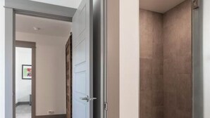 A modern bathroom with a shower area, a door leading to another room, and a hallway with a carpeted floor. - Rainbow Haven down by the Gallatin River (Bozeman)