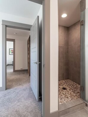 Shower area with a pebble-textured floor and glass door.