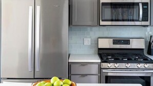 A kitchen with grey cabinets, a stainless steel refrigerator, a microwave, and a stove. - Rainbow Haven down by the Gallatin River (Bozeman)