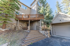 A two-story house with a wooden deck, stone steps, and a garage. - 217 Summerwood Drive by Summit County Mountain Retreats (Dillon)