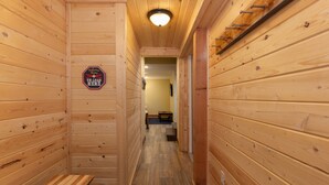 A wooden interior hallway with a bench, a sign reading "Welcome, Unload Here," and a door leading to another room. - 8 Crown Drive by Summit County Mountain Retreats (Breckenridge)
