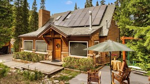A log cabin with a deck, large windows, and a chimney.
