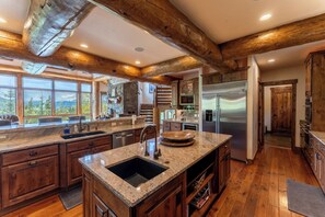A spacious kitchen with wooden beams, granite countertops, and a large island. - 227 North Fork Road by Summit County Mountain Retreats (Keystone)