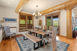 A dining area with a wooden table, benches, and a chandelier.