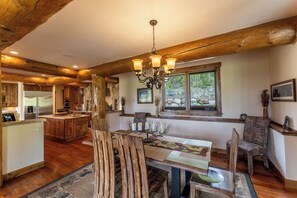 Una cocina amplia con vigas de madera, un comedor con candelabro y vistas al exterior.