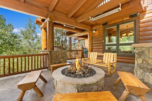 A wooden deck with a stone fire pit, wooden benches, and a stone wall. - 227 North Fork Road by Summit County Mountain Retreats (Keystone)