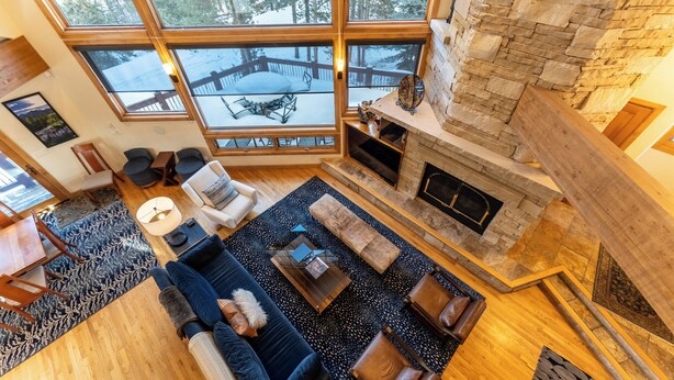 A spacious living room with a fireplace, large windows, and a cozy seating area.