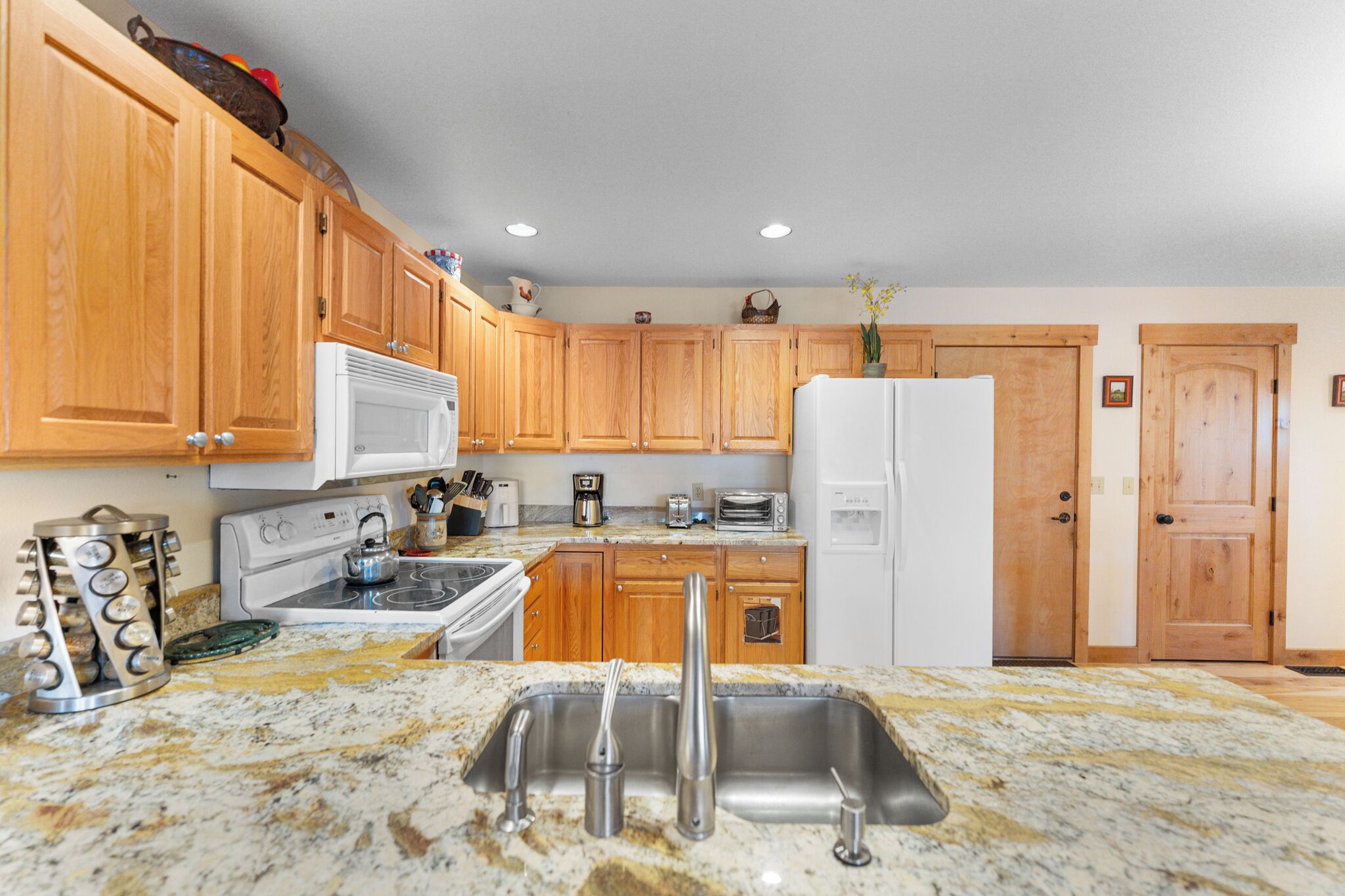 A kitchen with wooden cabinets, a white refrigerator, a stove, a sink, and a countertop with various appliances and utensils.