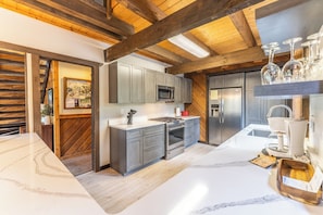 A modern kitchen with grey cabinets, a built-in microwave, stainless steel appliances, and a marble countertop. - 0238 Wild Irishman Road by Summit County Mountain Retreats (Keystone)