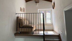 Una escalera con detalles de madera, barandilla de metal y vistas a una puerta con panel de vidrio.