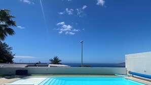 Une piscine sur le toit offrant une vue dégagée sur l’océan et un ciel bleu.