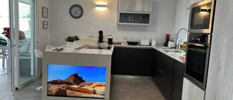 Une cuisine moderne équipée d’un téléviseur encastré, d’un four à micro-ondes et d’un grille-pain.