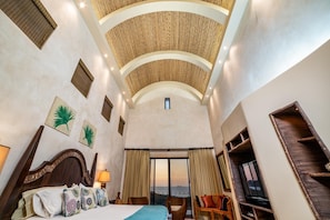 A hotel room with a bed, a chair, a TV, and a view of the sea. - Villa Sahalee (Cabo Velas)