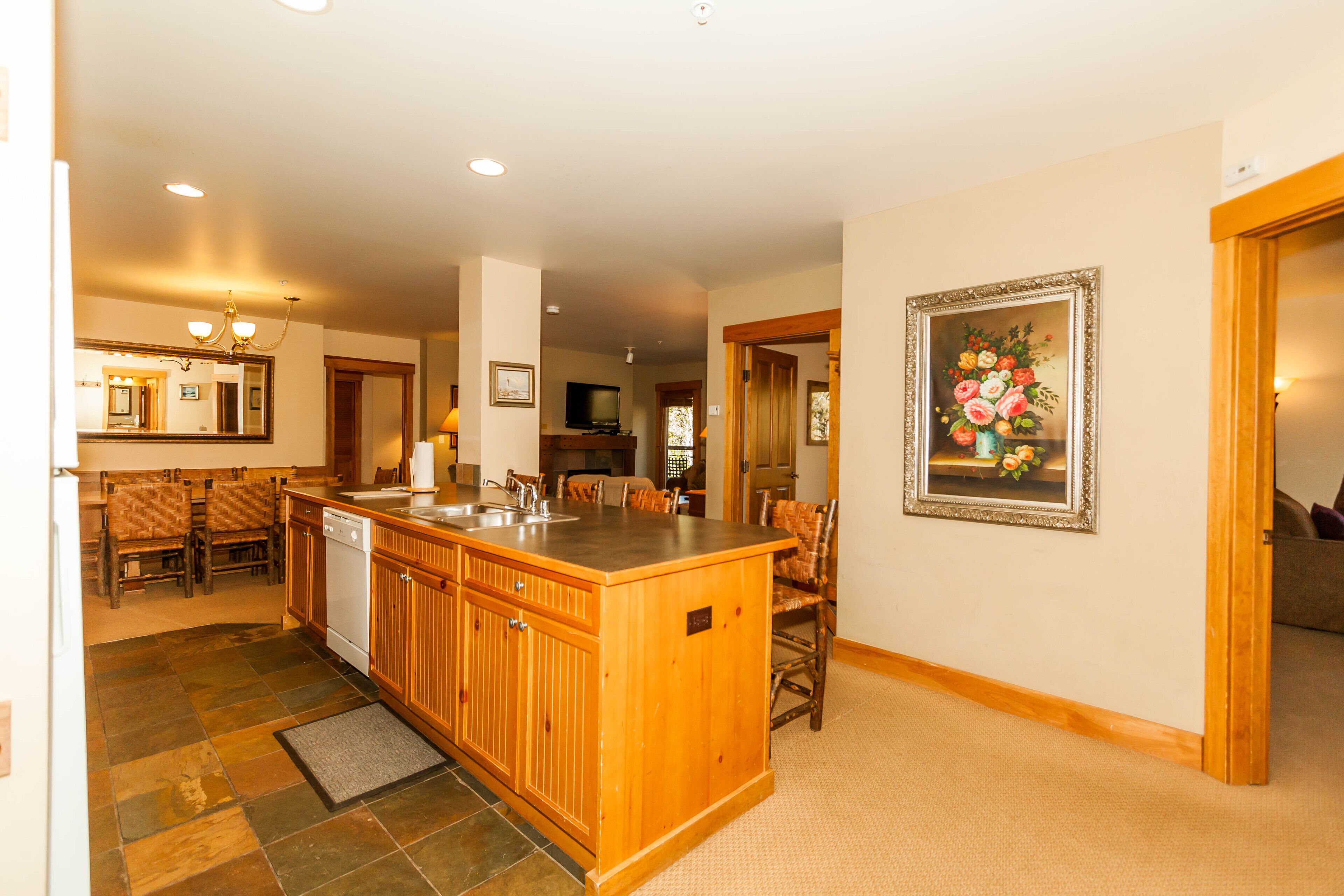A spacious kitchen with a central island, wooden cabinets, and a dining area with chairs.