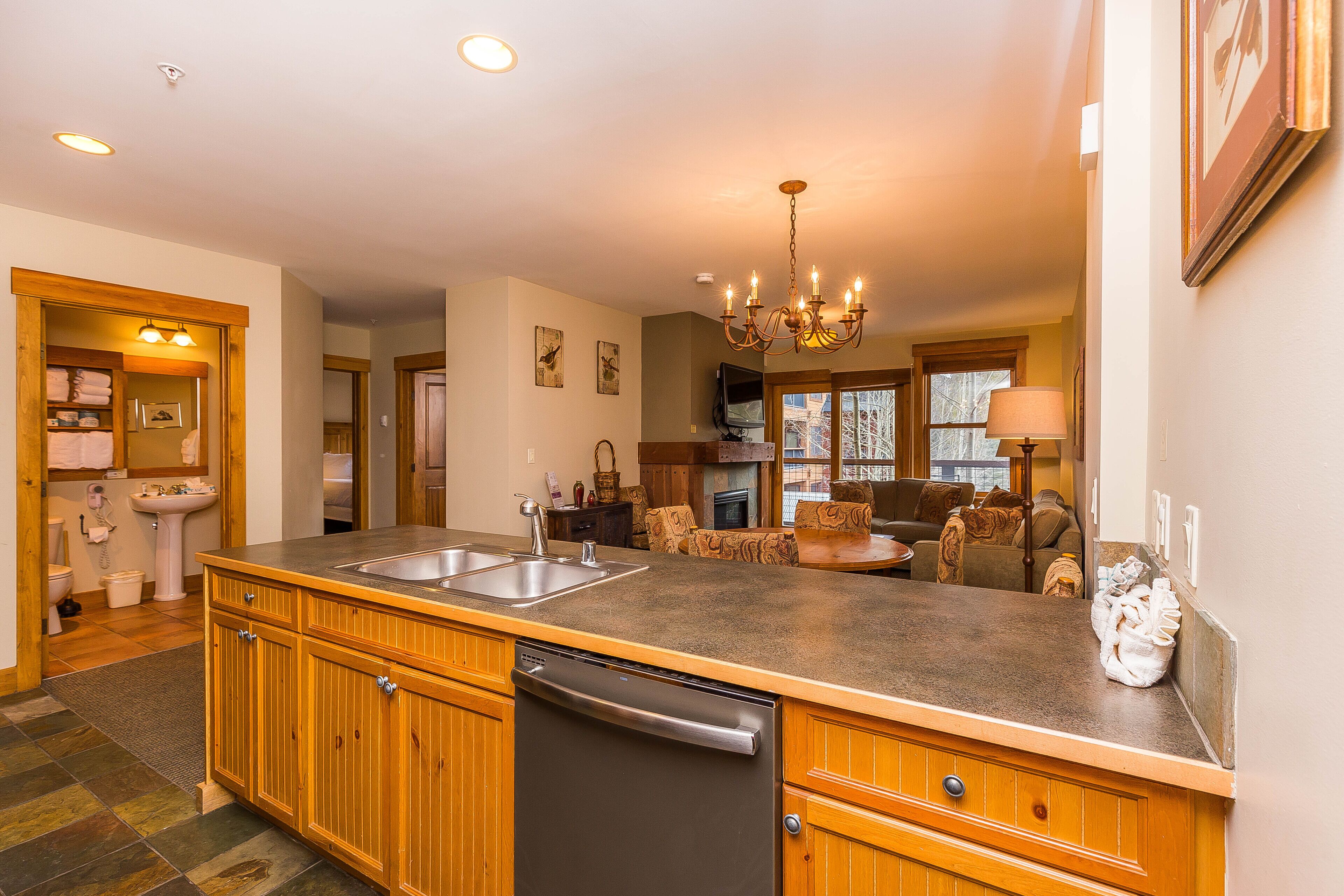 A spacious kitchen with wooden cabinets, a dishwasher, and a large island with a sink.
