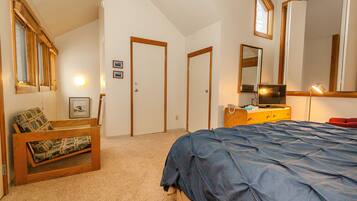 A bedroom with a bed, a wooden bench, a dresser, and a mirror.
