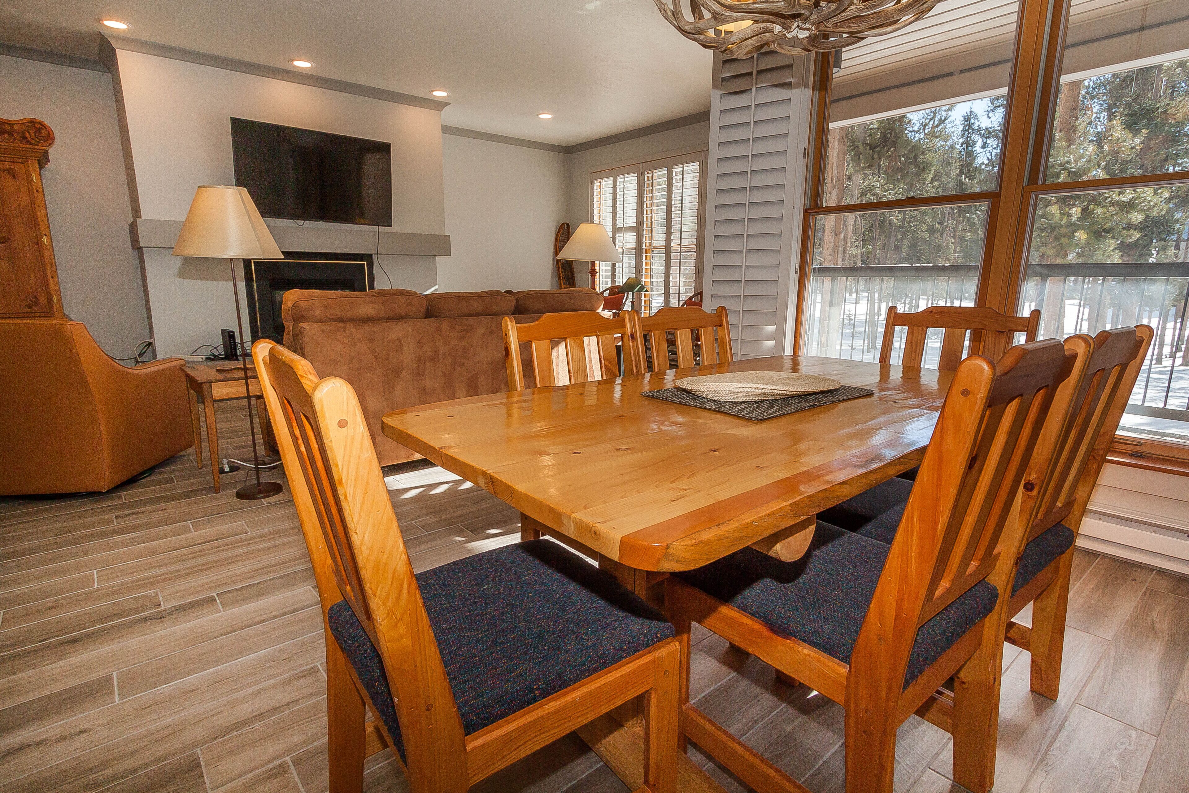 A dining area with a wooden table and chairs, a sofa, and a television mounted on the wall.